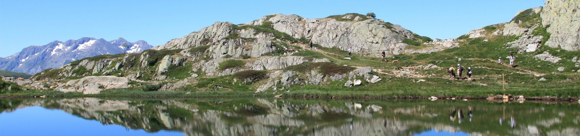 Randonneurs près d'un lac de montagne et sommets reflétés - Alpes françaises - France