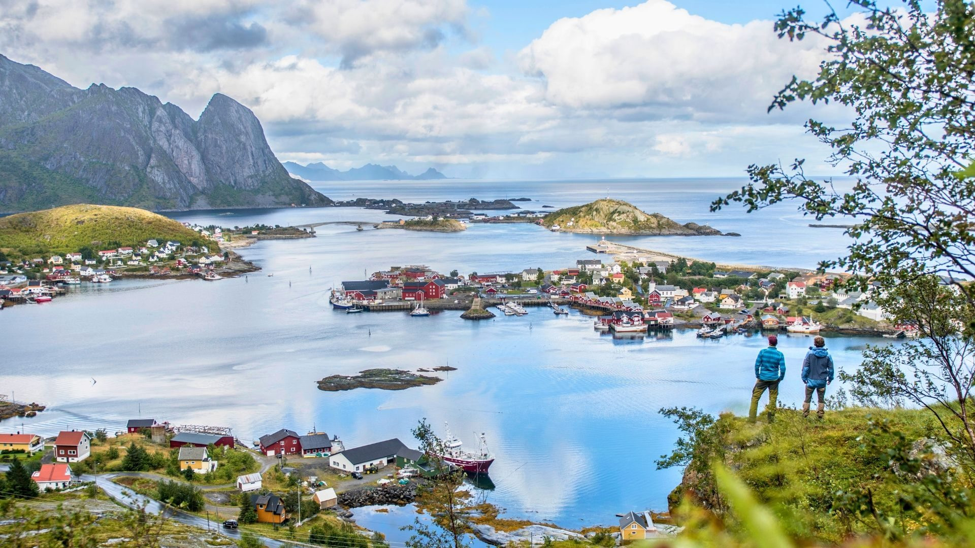Randonneurs face à un village de pêcheurs - Îles Lofoten - Norvège